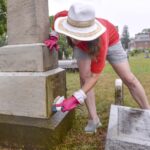 woman cleaning monument at graveyard